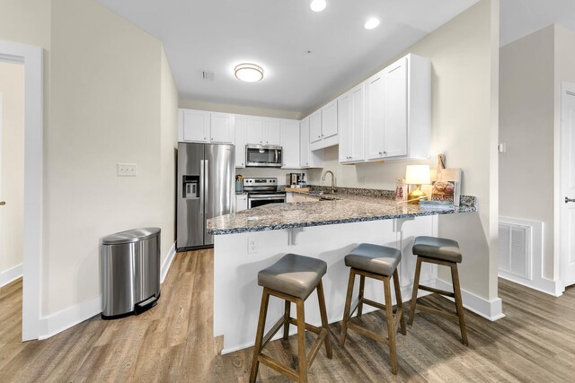 kitchen with sink, light hardwood / wood-style flooring, stainless steel appliances, and white cabinets