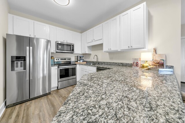 kitchen with light hardwood / wood-style flooring, appliances with stainless steel finishes, and white cabinetry