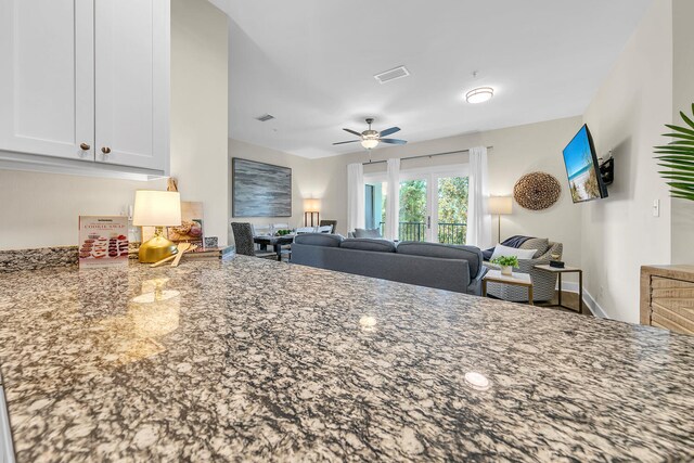 kitchen with white cabinetry, ceiling fan, and light stone counters