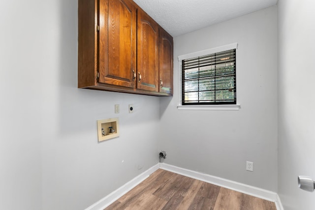 washroom featuring cabinets, washer hookup, a textured ceiling, electric dryer hookup, and hardwood / wood-style floors