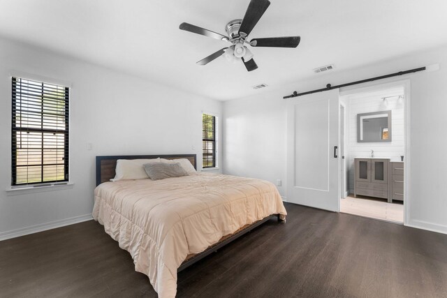 bedroom with ceiling fan, dark hardwood / wood-style floors, and a barn door