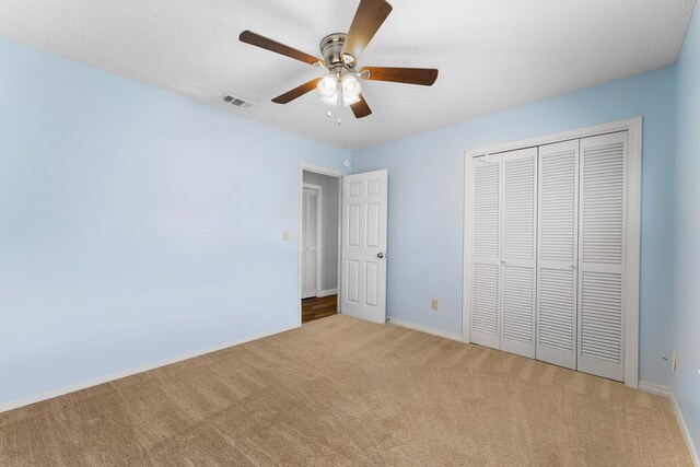 unfurnished bedroom with ceiling fan, light colored carpet, and a closet