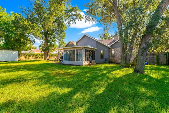 rear view of house with a lawn and a sunroom