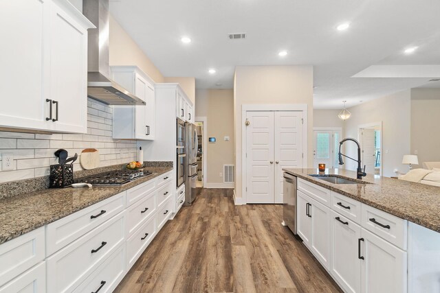 kitchen featuring hardwood / wood-style flooring, sink, white cabinetry, stone counters, and wall chimney exhaust hood