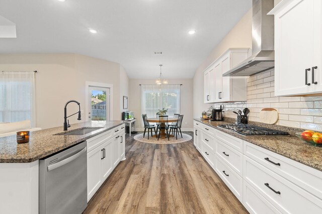 kitchen with white cabinets, stainless steel appliances, light wood-type flooring, sink, and wall chimney range hood