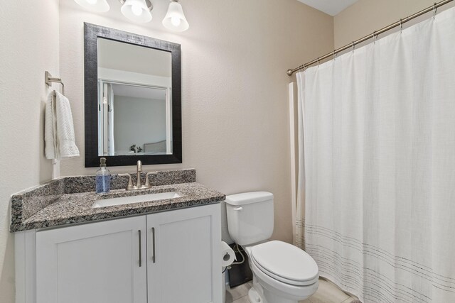 bathroom with a shower with curtain, vanity, toilet, and tile patterned floors