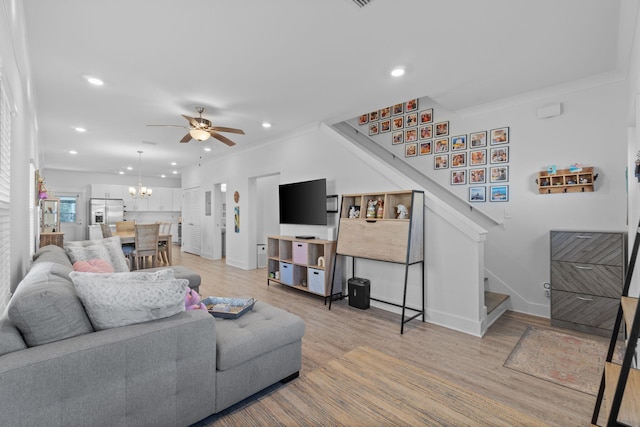 living room featuring light hardwood / wood-style flooring, ceiling fan with notable chandelier, and ornamental molding