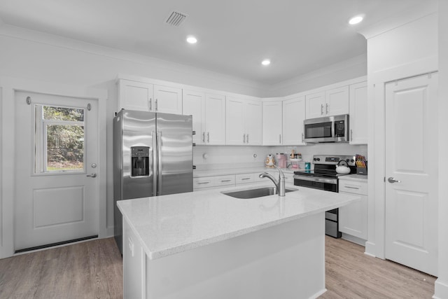 kitchen featuring white cabinets, stainless steel appliances, light stone countertops, and an island with sink