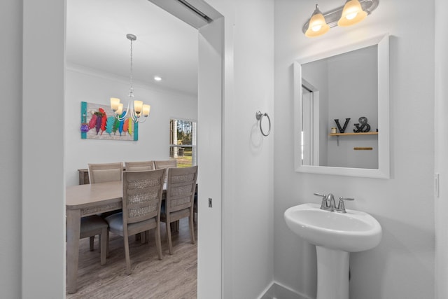 bathroom featuring hardwood / wood-style flooring, a notable chandelier, sink, and crown molding