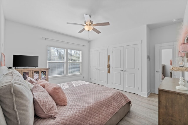 bedroom featuring multiple closets, ceiling fan, and light hardwood / wood-style flooring