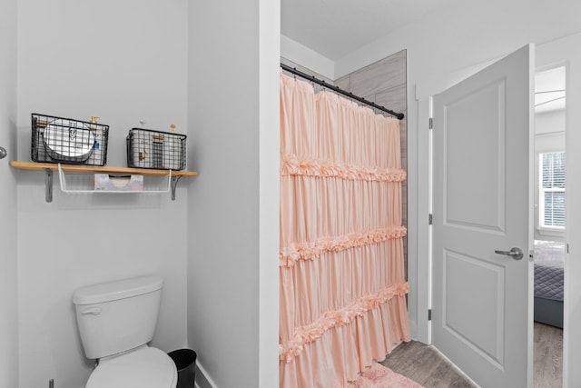 bathroom featuring hardwood / wood-style flooring, curtained shower, and toilet