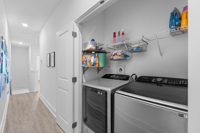 clothes washing area featuring separate washer and dryer and light hardwood / wood-style flooring