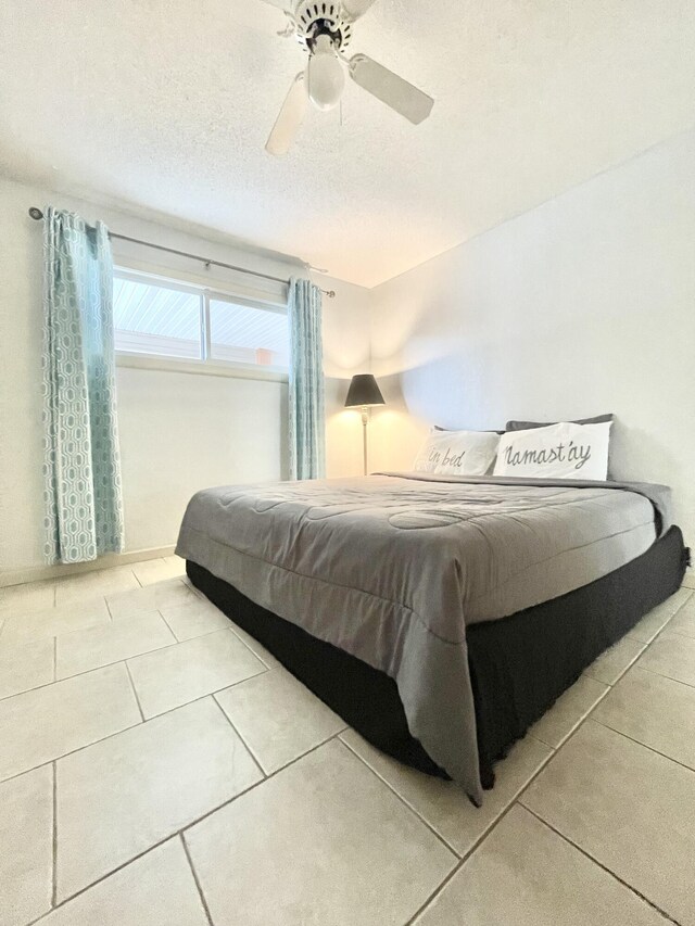 tiled bedroom featuring ceiling fan and a textured ceiling