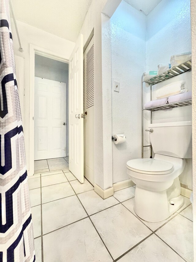 bathroom with baseboards, toilet, and tile patterned floors