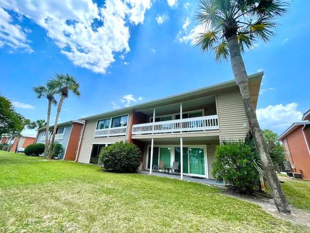 back of property with a lawn, a patio area, and a balcony