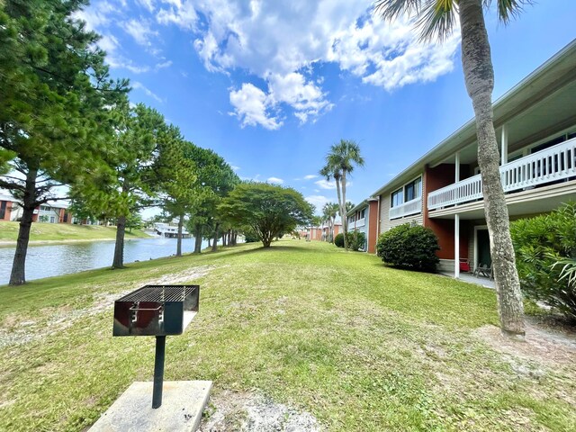 view of property's community with a water view and a lawn