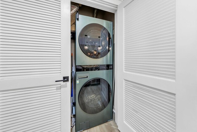 laundry area with stacked washer and dryer and light hardwood / wood-style flooring