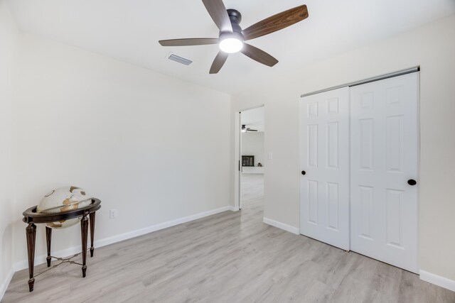 unfurnished bedroom with light hardwood / wood-style floors, ceiling fan, and a closet