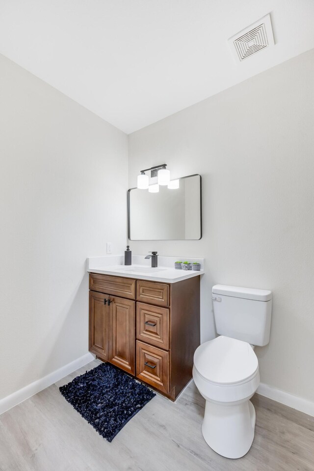 bathroom featuring wood-type flooring, vanity, and toilet