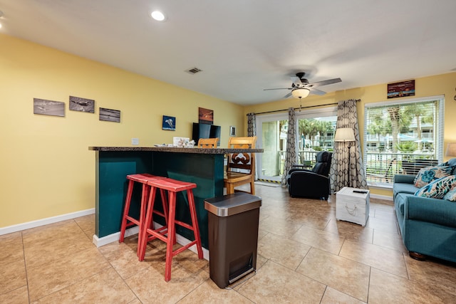 kitchen with ceiling fan, a kitchen bar, and light tile patterned floors