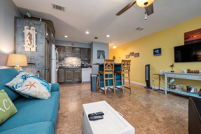 living room featuring a textured ceiling, light tile patterned flooring, sink, and ceiling fan