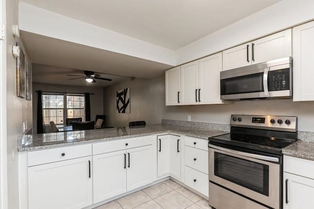 kitchen featuring light tile patterned floors, a peninsula, white cabinetry, appliances with stainless steel finishes, and light stone countertops