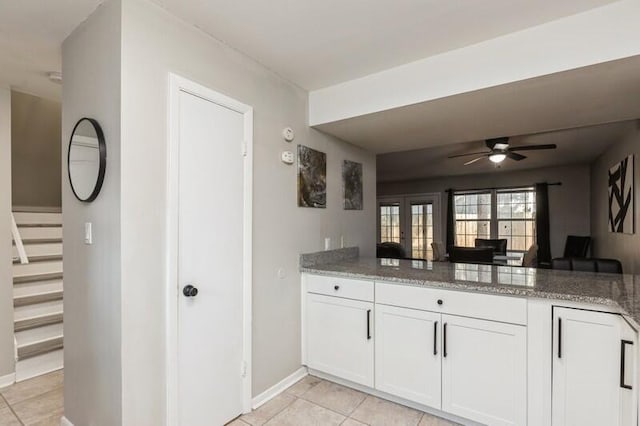 kitchen with open floor plan, a peninsula, dark stone countertops, and white cabinetry