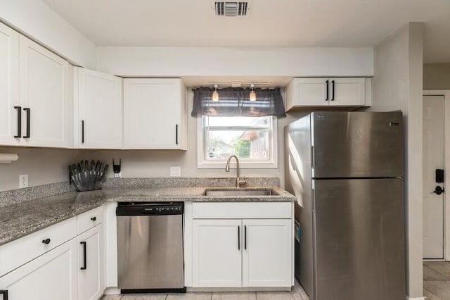 kitchen featuring stainless steel appliances, visible vents, white cabinets, a sink, and dark stone countertops