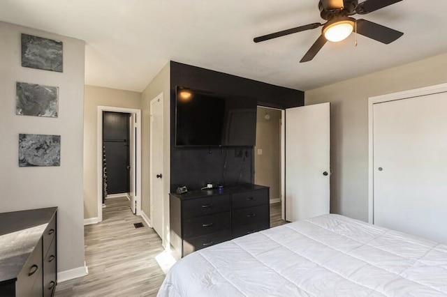 bedroom with light wood-type flooring, visible vents, baseboards, and a ceiling fan