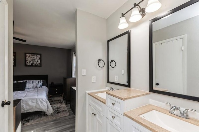 ensuite bathroom with a sink, double vanity, wood finished floors, and connected bathroom