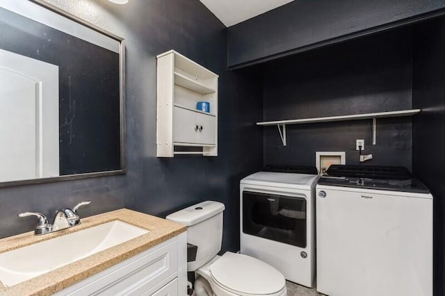 bathroom featuring washing machine and dryer, vanity, and toilet