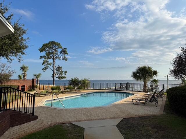 view of swimming pool featuring a patio and a water view