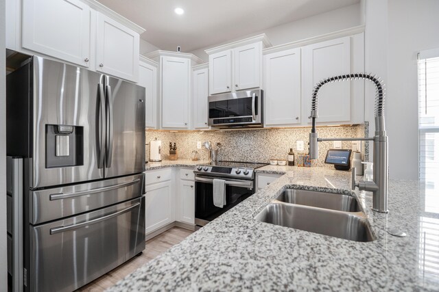 kitchen featuring light wood-type flooring, sink, white cabinetry, appliances with stainless steel finishes, and light stone countertops