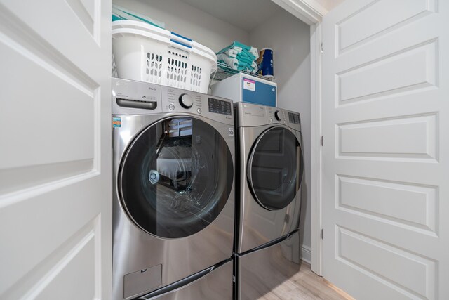 laundry area with light wood-type flooring and separate washer and dryer