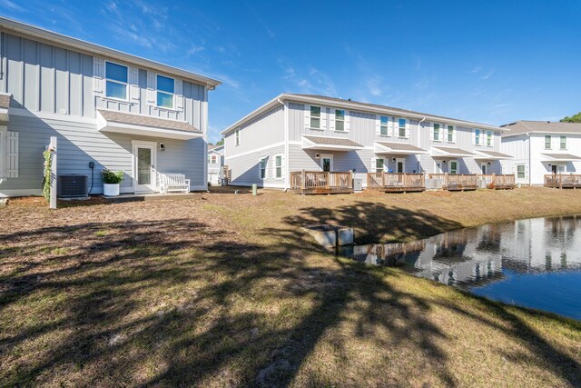 rear view of house with a lawn, a wooden deck, and central AC