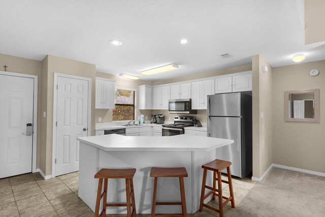 kitchen with appliances with stainless steel finishes, white cabinetry, a kitchen island, and a kitchen breakfast bar