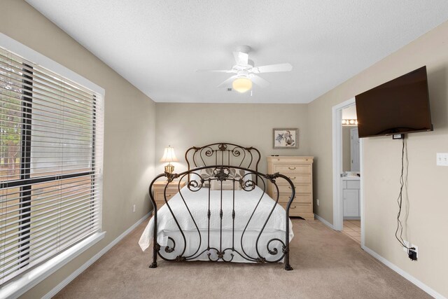 bedroom featuring ensuite bath, ceiling fan, light colored carpet, and a textured ceiling