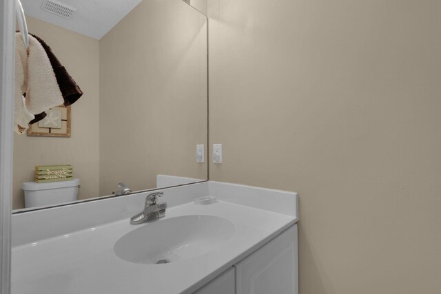 bathroom featuring vanity, toilet, and a textured ceiling