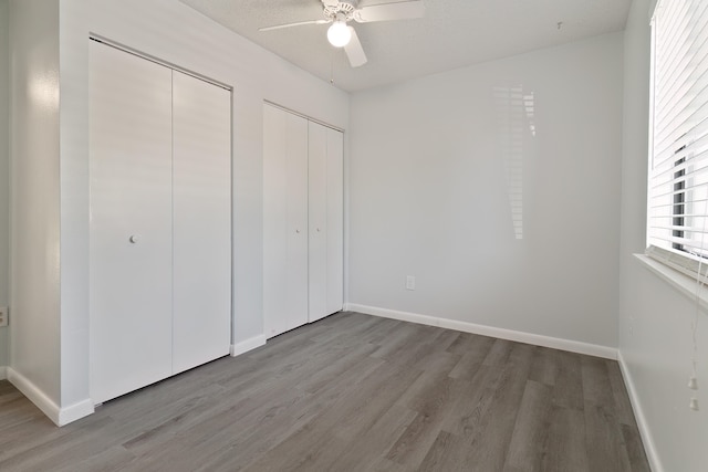 unfurnished bedroom with multiple closets, ceiling fan, light hardwood / wood-style floors, and a textured ceiling