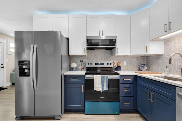 kitchen featuring blue cabinetry, stainless steel appliances, white cabinetry, and sink