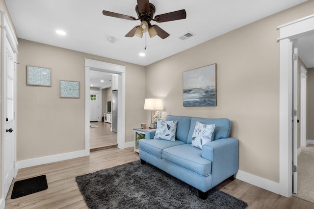 living room with light hardwood / wood-style floors and ceiling fan