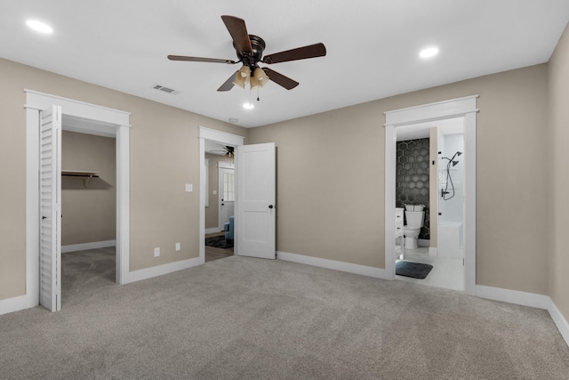 unfurnished bedroom with light carpet, ceiling fan, a spacious closet, connected bathroom, and a closet