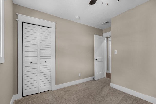 unfurnished bedroom with light carpet, a closet, and ceiling fan