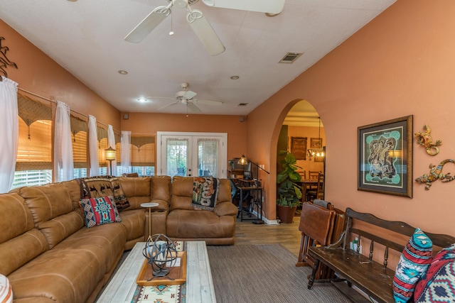 living room featuring wood-type flooring, ceiling fan with notable chandelier, and french doors