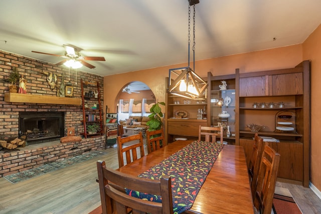 dining room with ceiling fan, a fireplace, and hardwood / wood-style floors