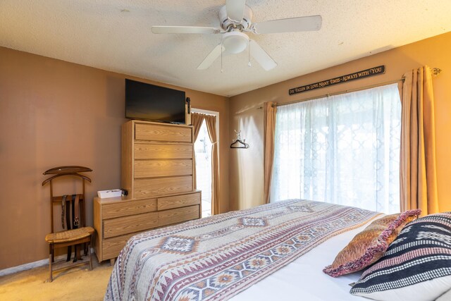 bedroom featuring ceiling fan, light colored carpet, and a textured ceiling