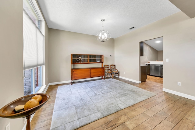 empty room featuring a textured ceiling, light hardwood / wood-style floors, and a healthy amount of sunlight