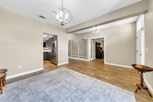 interior space featuring a textured ceiling, light hardwood / wood-style flooring, and a chandelier