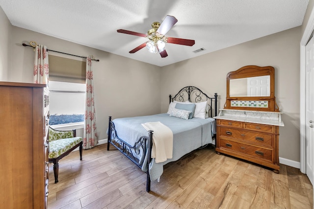 bedroom featuring light wood-type flooring, ceiling fan, and a textured ceiling