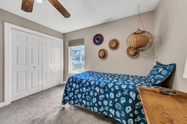 bedroom with a textured ceiling, carpet, ceiling fan, and a closet